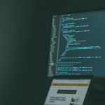 Programmer coding on two desktops